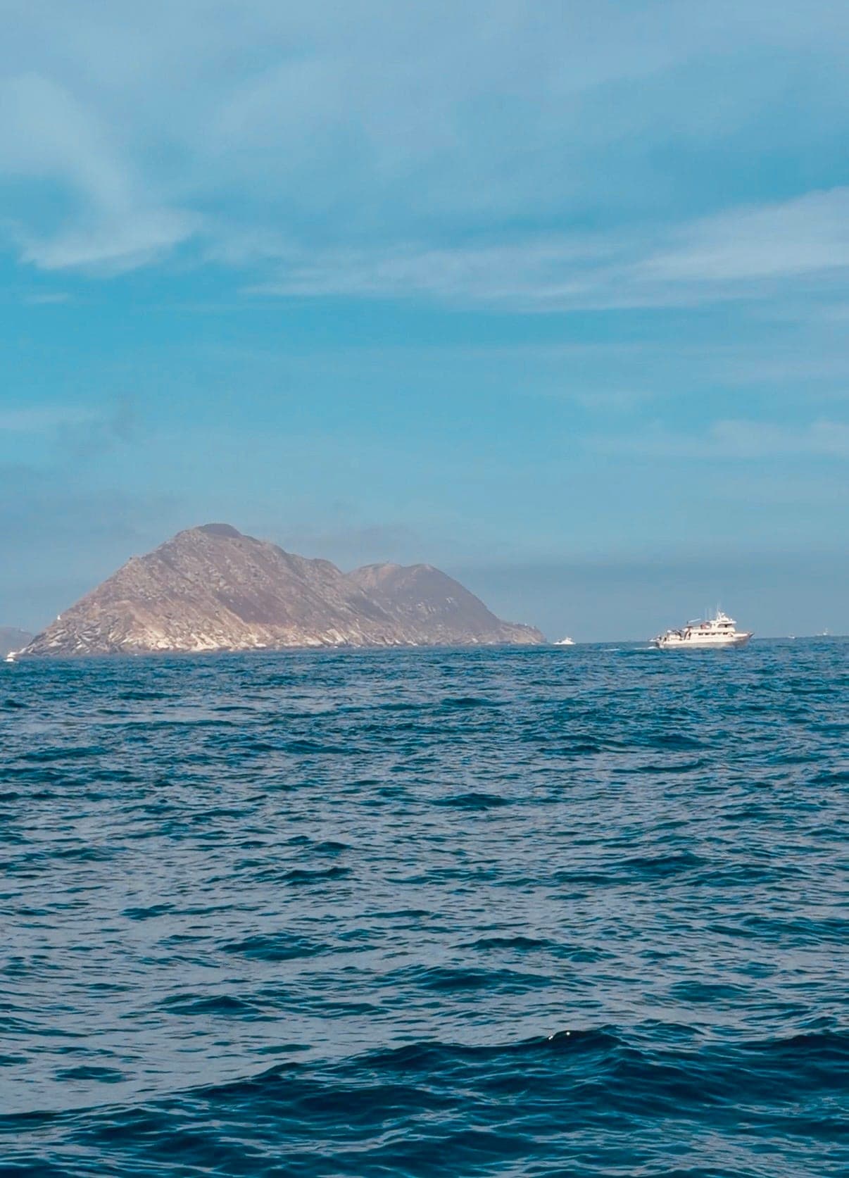 A sportfishing boat on blue water off the rocky Coronado Islands under a clear sky