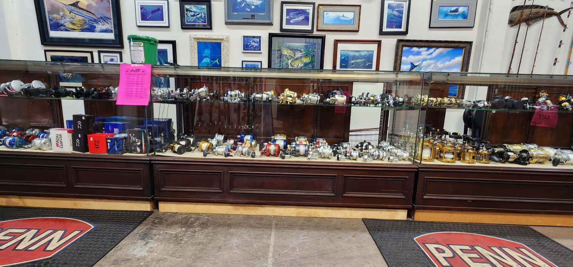 Inside San Diego Tackle Traders — glass counters lined with reels, framed ocean art, and Penn floor mats