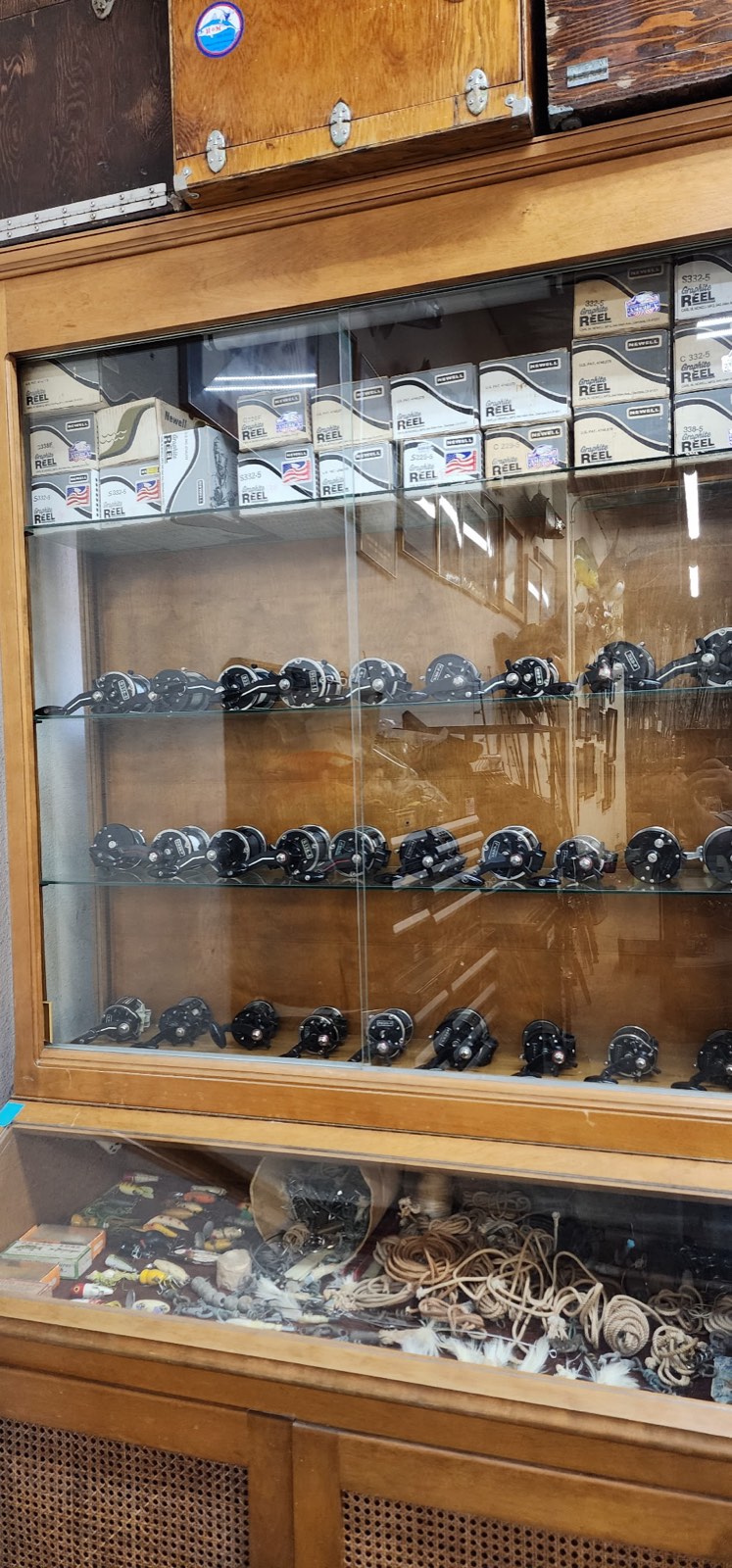 Wooden cabinet of vintage and collectible reels with boxed reels stacked on top