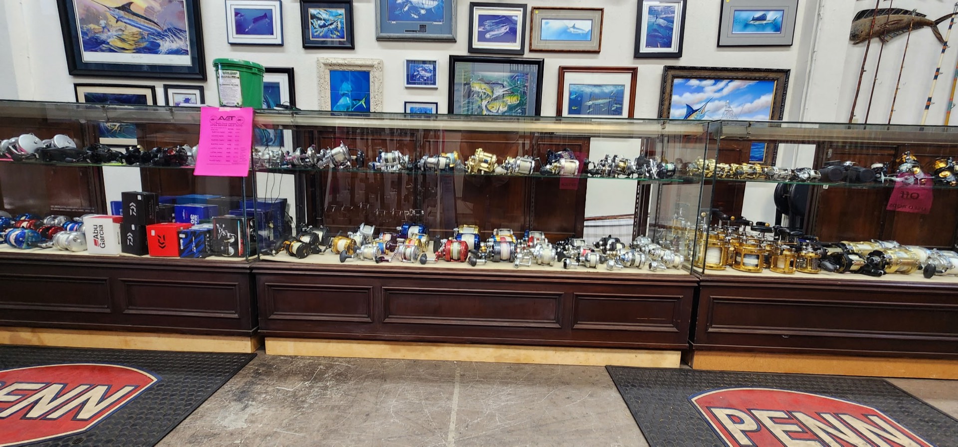 Inside San Diego Tackle Traders — glass counters lined with reels, framed ocean art, and Penn floor mats