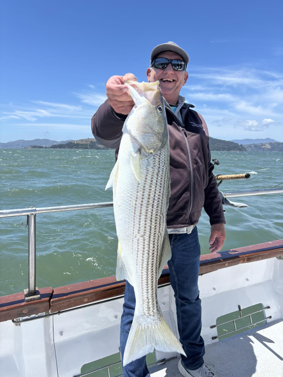 Striped Bass fishing at the Berkeley · San Francisco Bay — sport fishing boat with rocky islands in background